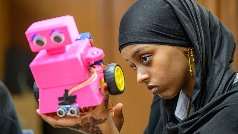 A competitor tweaking a pink rover robot