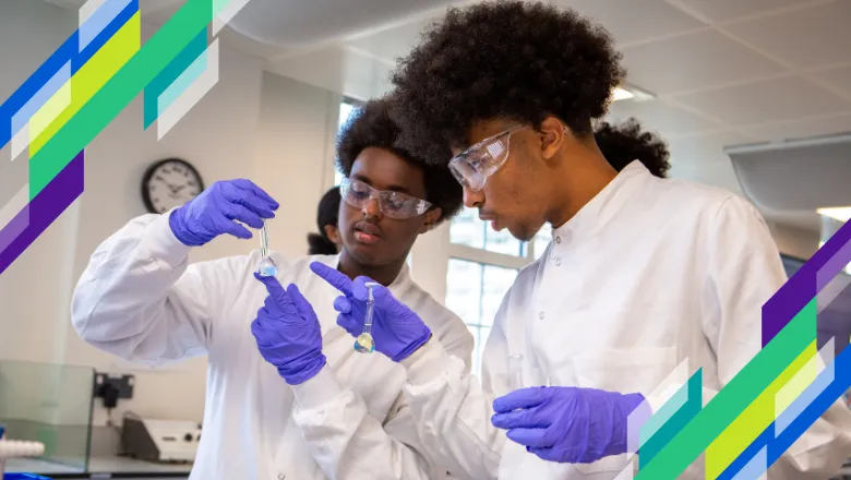 two students wearing white labcoats look at chemicals in small beakers