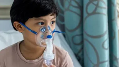 A sick boy in a hospital bed with a breathing mask