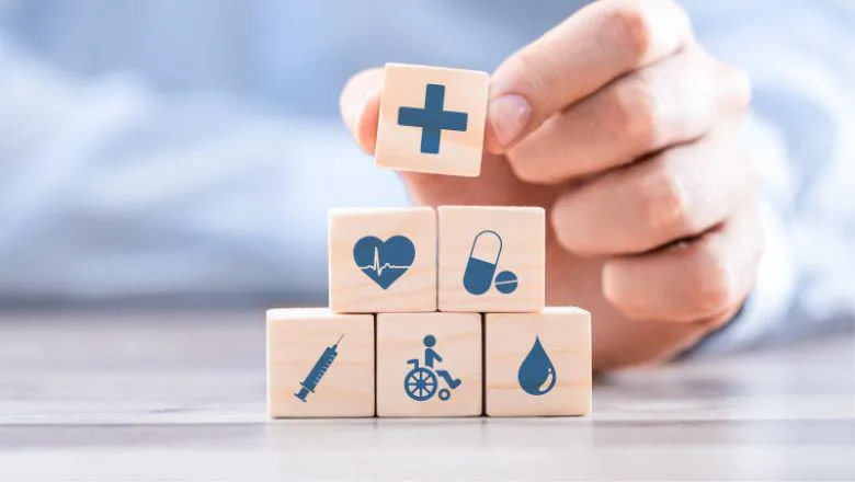 A hand stacking small wooden blocks with healthcare symbols on them