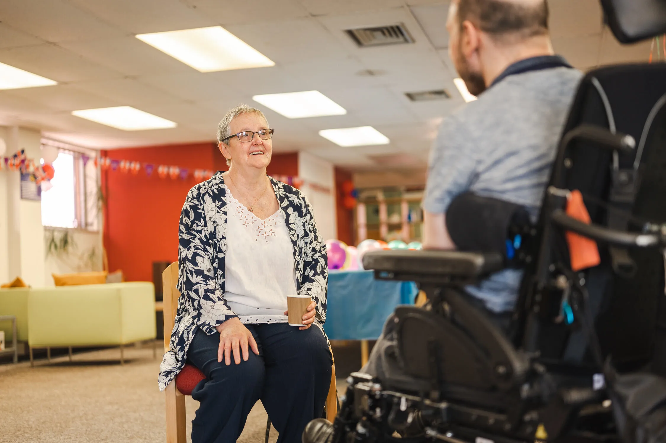 A woman speaking to a man in a wheelchair