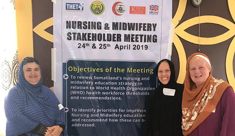 Three women standing next to a poster