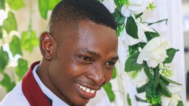 A man smiling stood next to a flower arch.