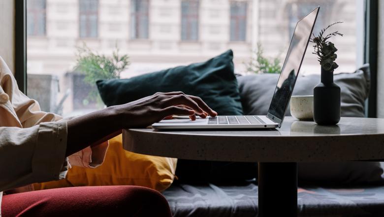 Person in red trousers sitting on sofa using laptop