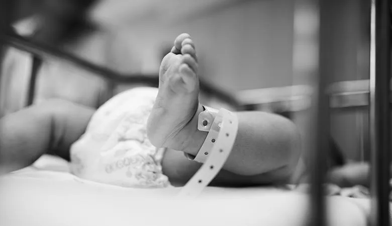 Black and white image of a new born baby in a cot.