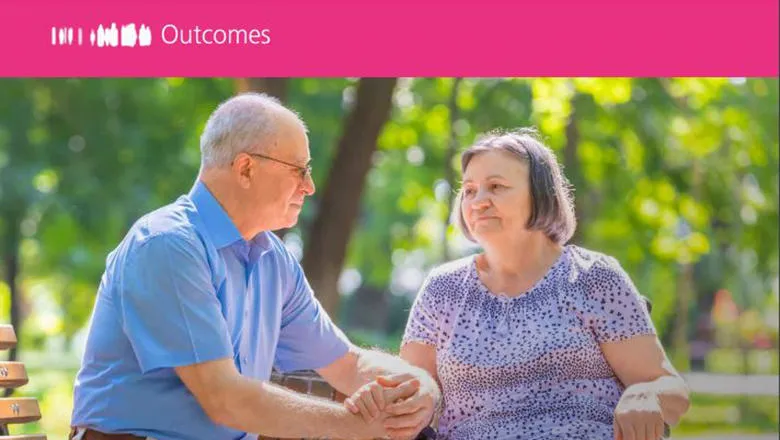 Man sitting on bench outside holding hand of woman in a wheelchair