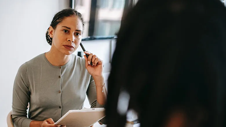 Woman sitting opposite a person holding a clipboard and pen