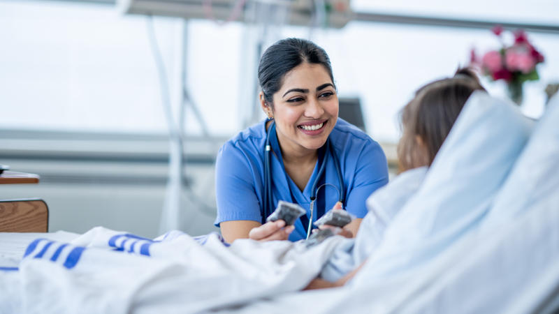 Nurse smiling at a child lying in a hospital bed