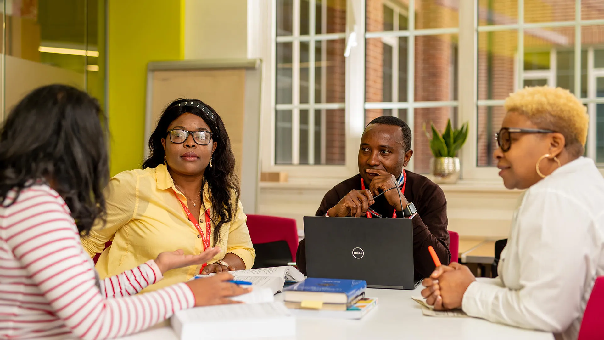 Four students in discussion seated round a table.