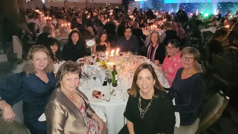 Jacqui and team sitting at table at awards ceremony