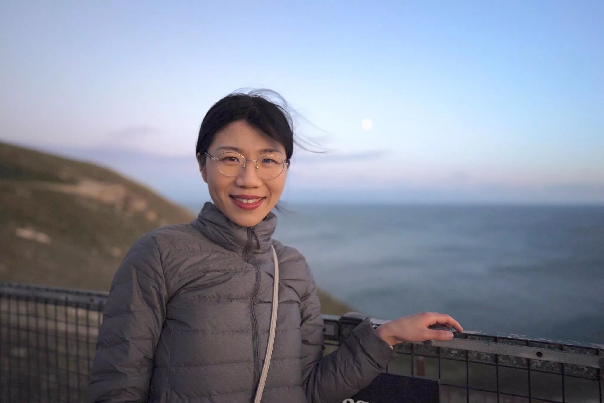Dr Jie Zhang standing in front of an ocean