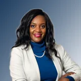 An image of Margaret Mutumba, a graduate of King's College London. She is wearing a white suit jacket, a blue top, and a pearl necklace.