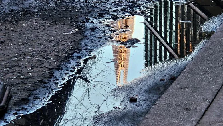 A pothole puddle reflects the Shard building
