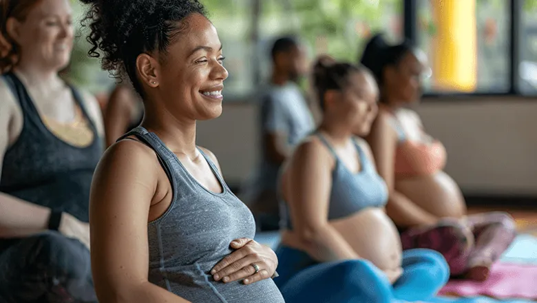 A group of pregnant women in sports wear sitting on yoga mats.
