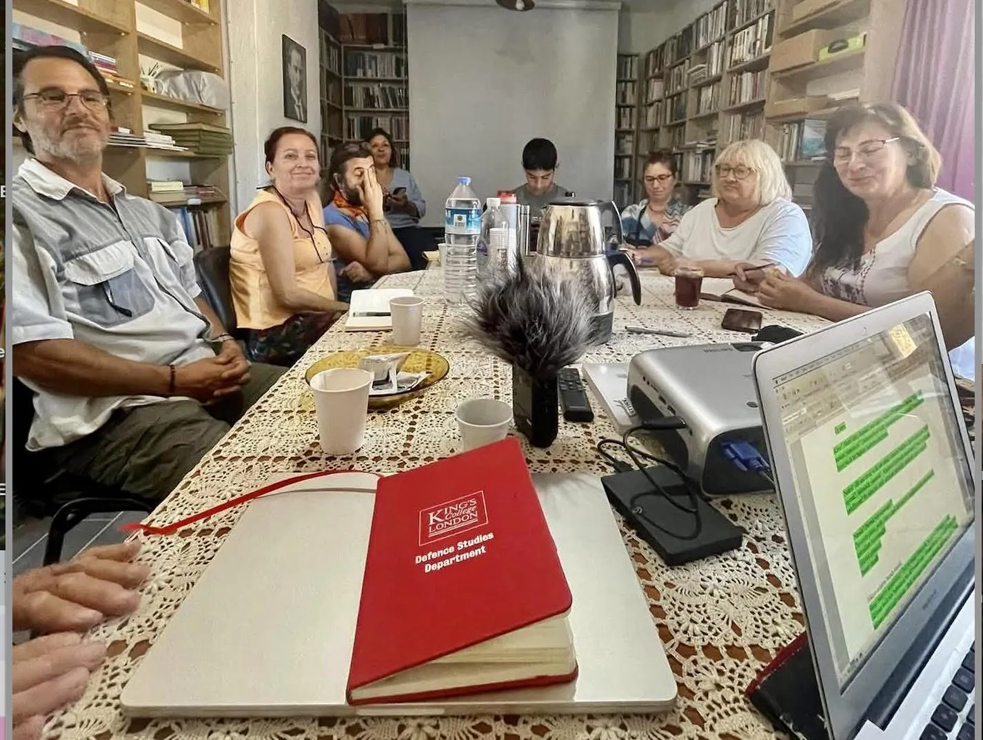 A group of people sit around a dining table in discussion,