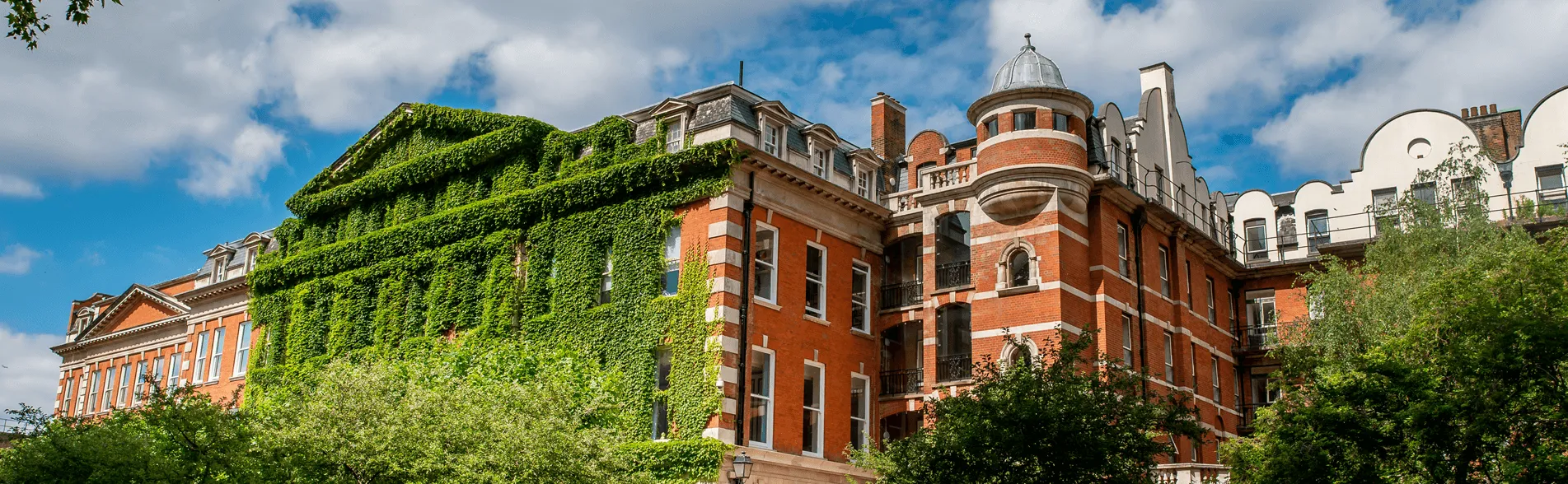 A red brick building covered in ivy on a sunny a day.
