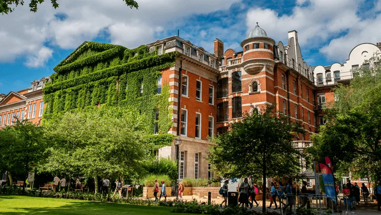 A red brick building covered in ivy on a sunny a day.