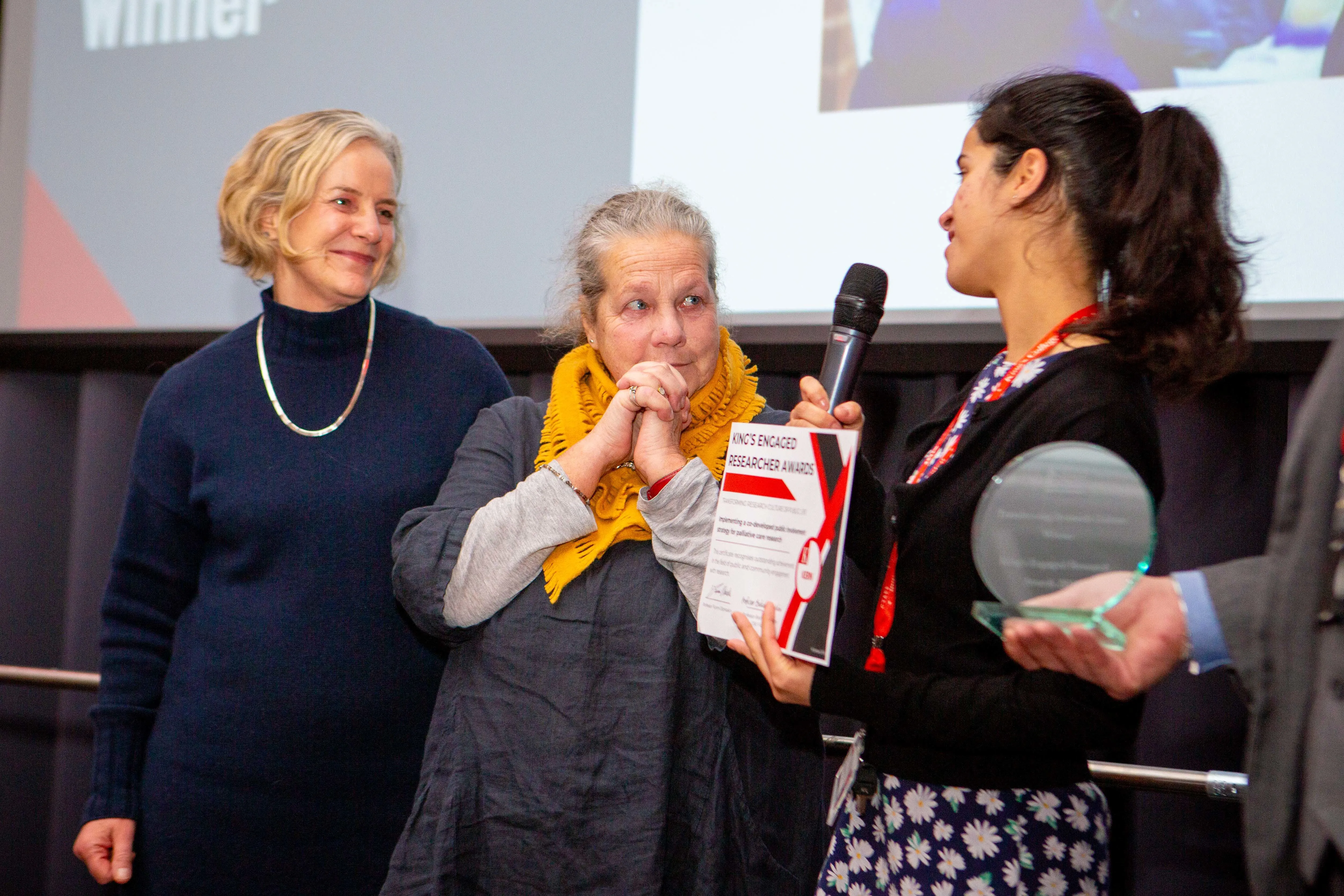 project team for Implementing a co-developed public involvement strategy for palliative care research receiving award certificate on stage