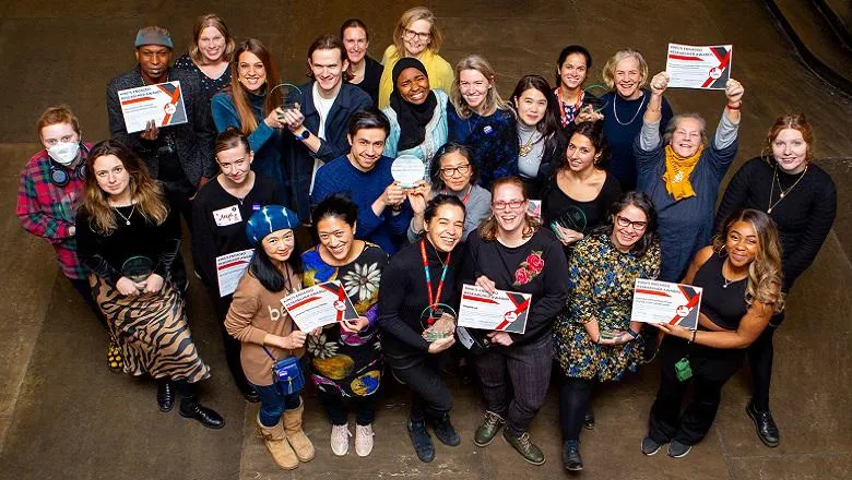 Aerial photo of all winners of king's engaged research awards 2024 looking upwards, some holding awards and certificates