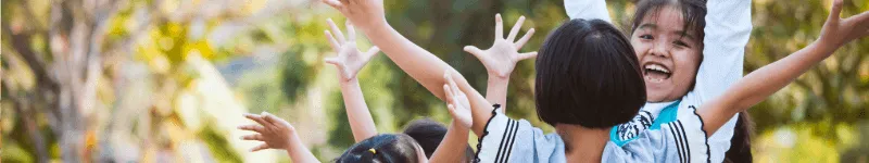 A group of happy children with their arms raised in joy.