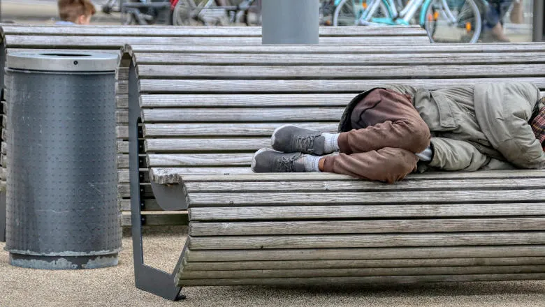 Disheveled person sleeping rough on a park bench