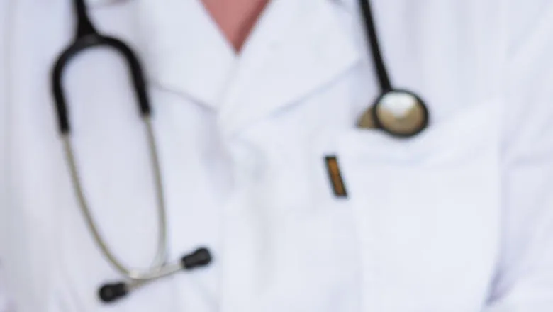 A stethoscope around the neck of someone in a white coat