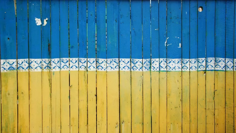 Blue and yellow fence with white patterned border in the middle, representing colours in the Ukranian flag.