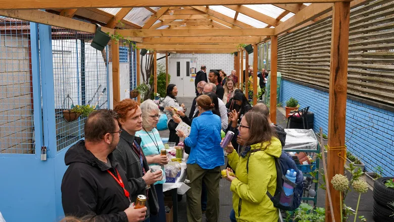 Crowd of staff members gathered in Denmark Hill Community Garden chatting.