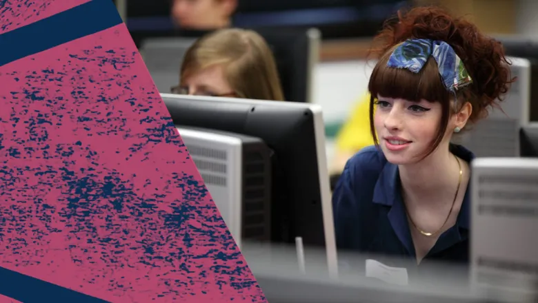 A woman looking at the computer in a room of computers