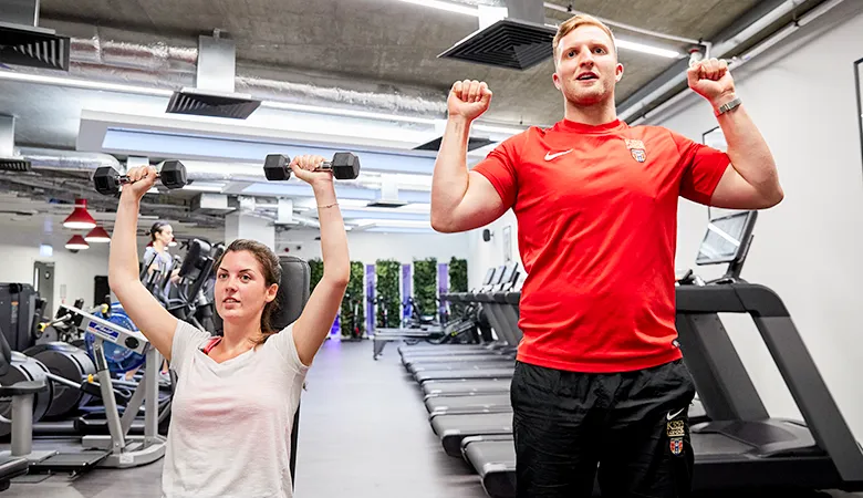 Gym Coach demonstrating correct form to member. 