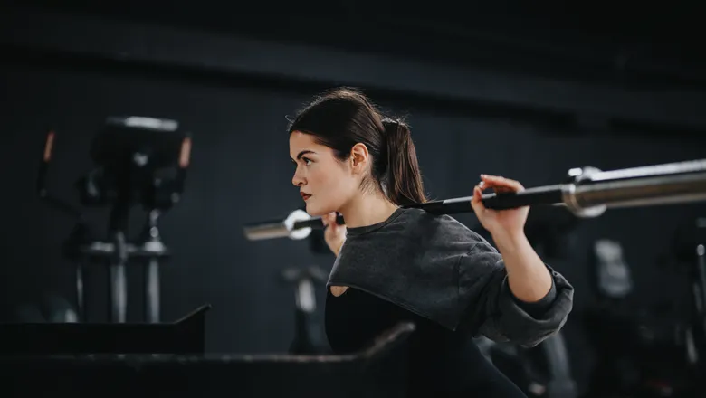 Woman squatting while lifting a weight training bar