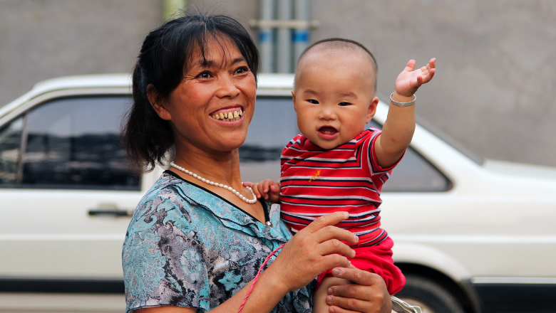 Smiling mother holding smiling baby who is waving
