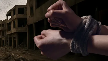 two hands tied up in front of war torn background 1800x500