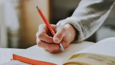 Close-up image of a person writing in a notebook