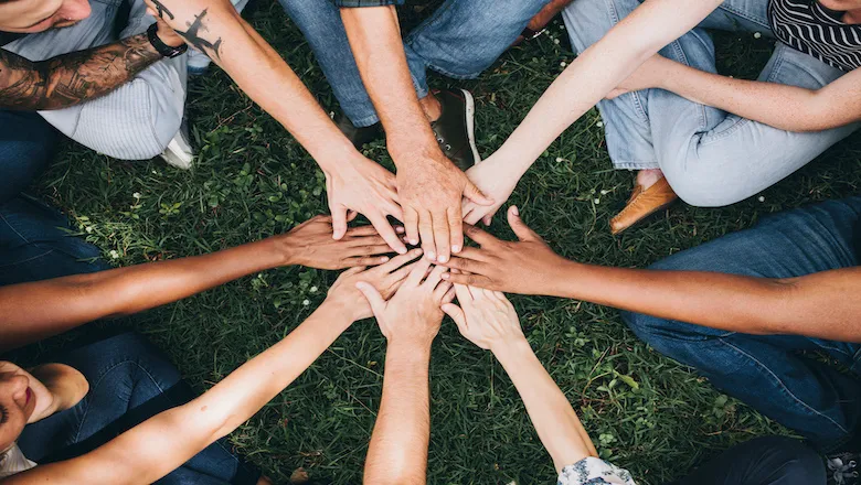 people stacking hands together in park