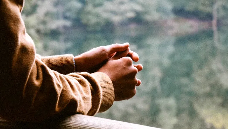 Arms and hands of someone looking over a lake