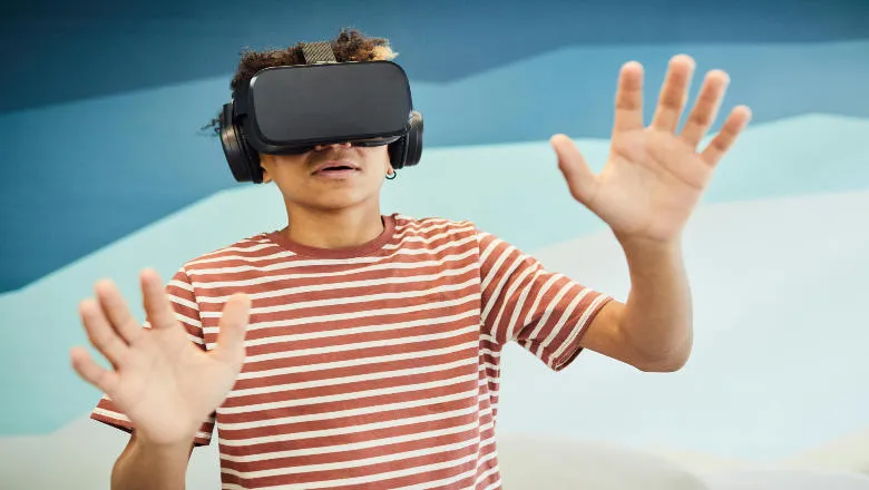 Boy wearing a virtual reality headset with hands outstretched