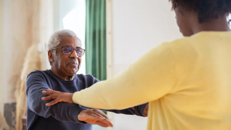 A care worker helps an older person with flexibility exercises