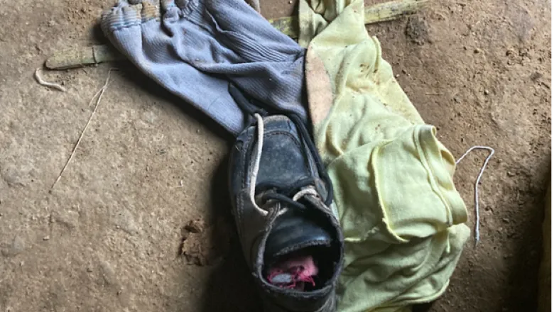 A shoe, small trousers and top layed on the ground