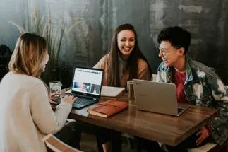 3 people chatting over laptops by brooke-cagle