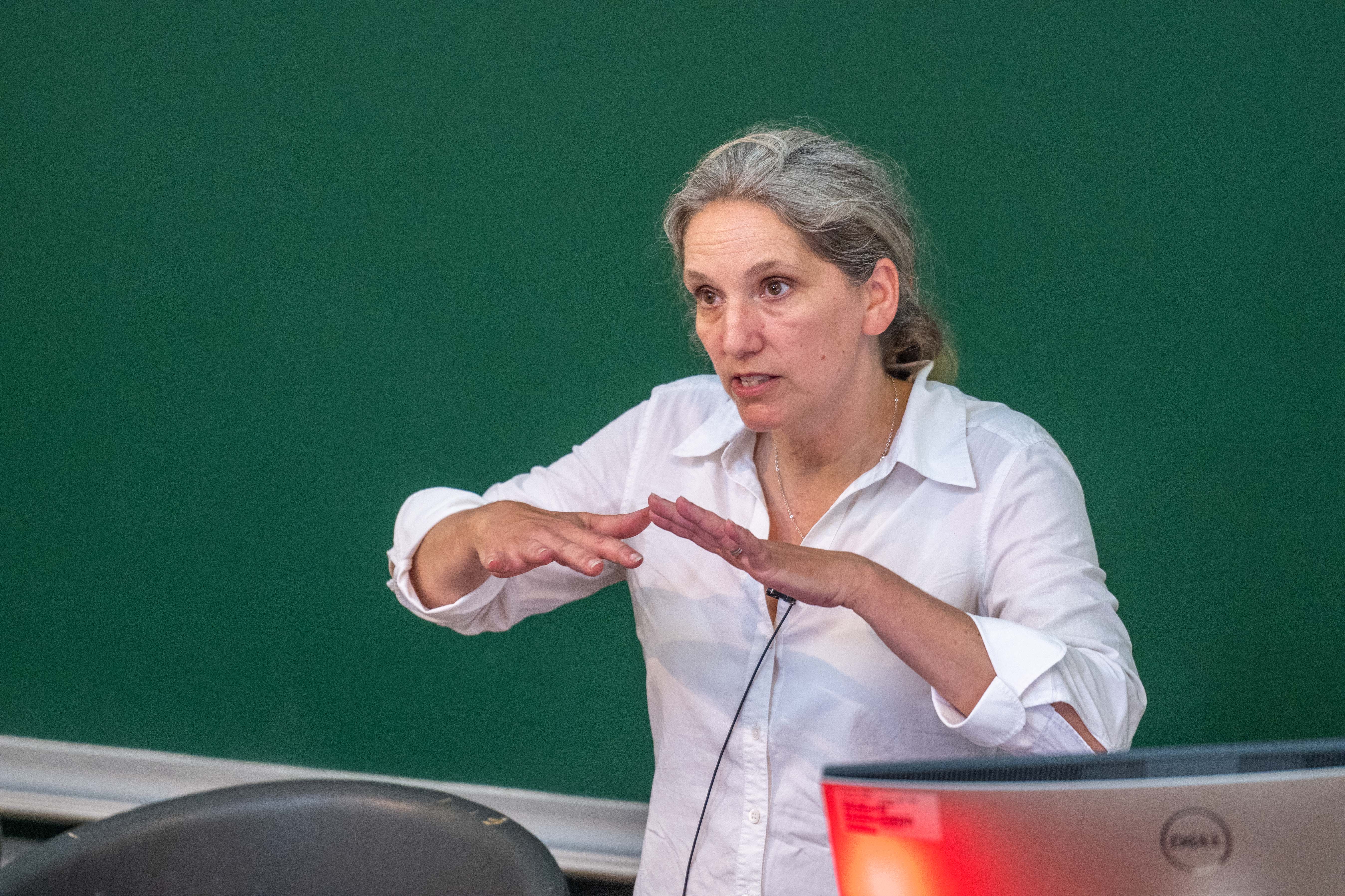 white woman in white shirt delivering speech using her hands to emote