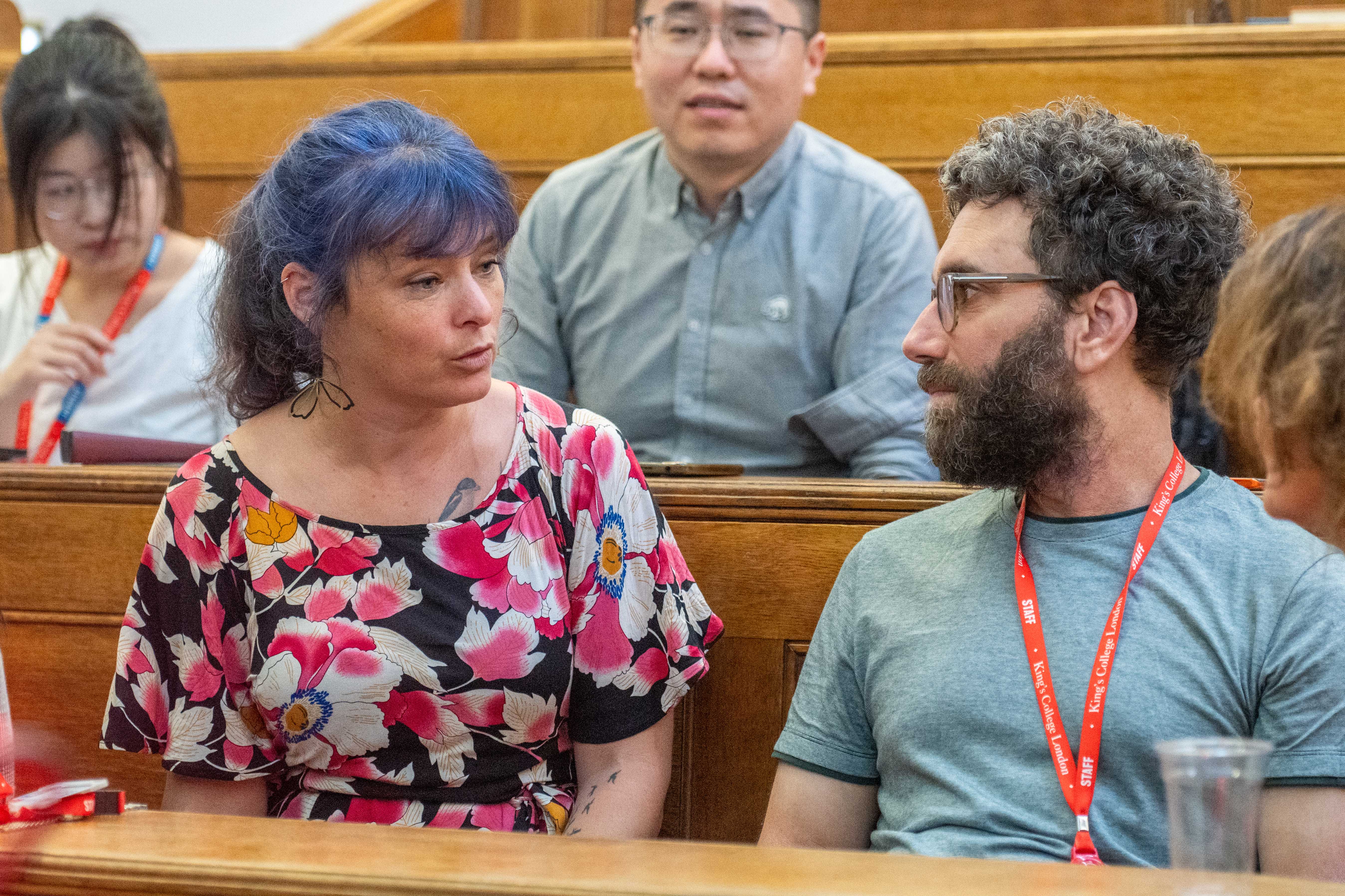 group discussion with white woman with blue hair, asian man in glasses and shirt, white man with short curly dark hair