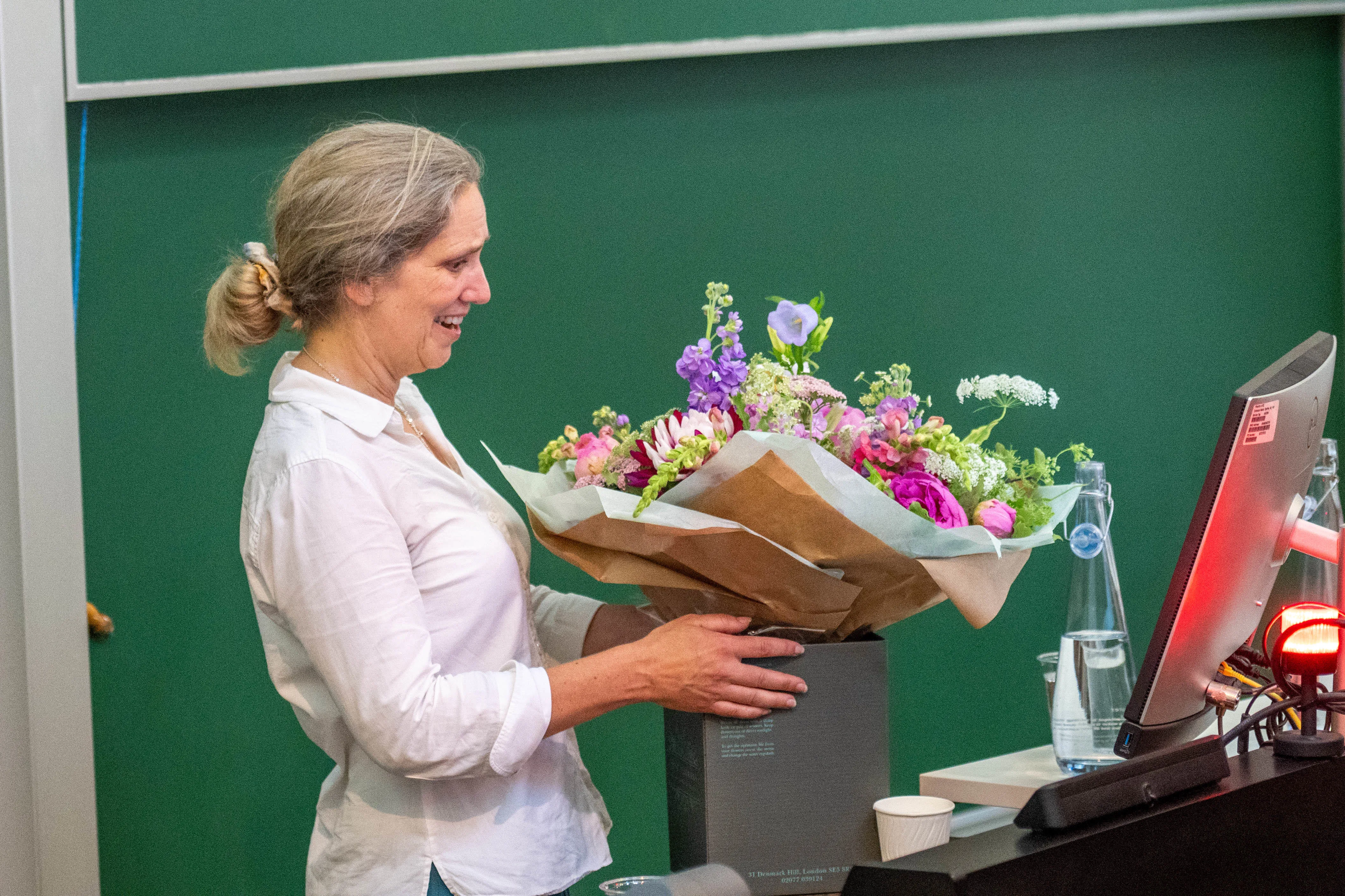 white woman in white shirt receiving large bouquet of flowers