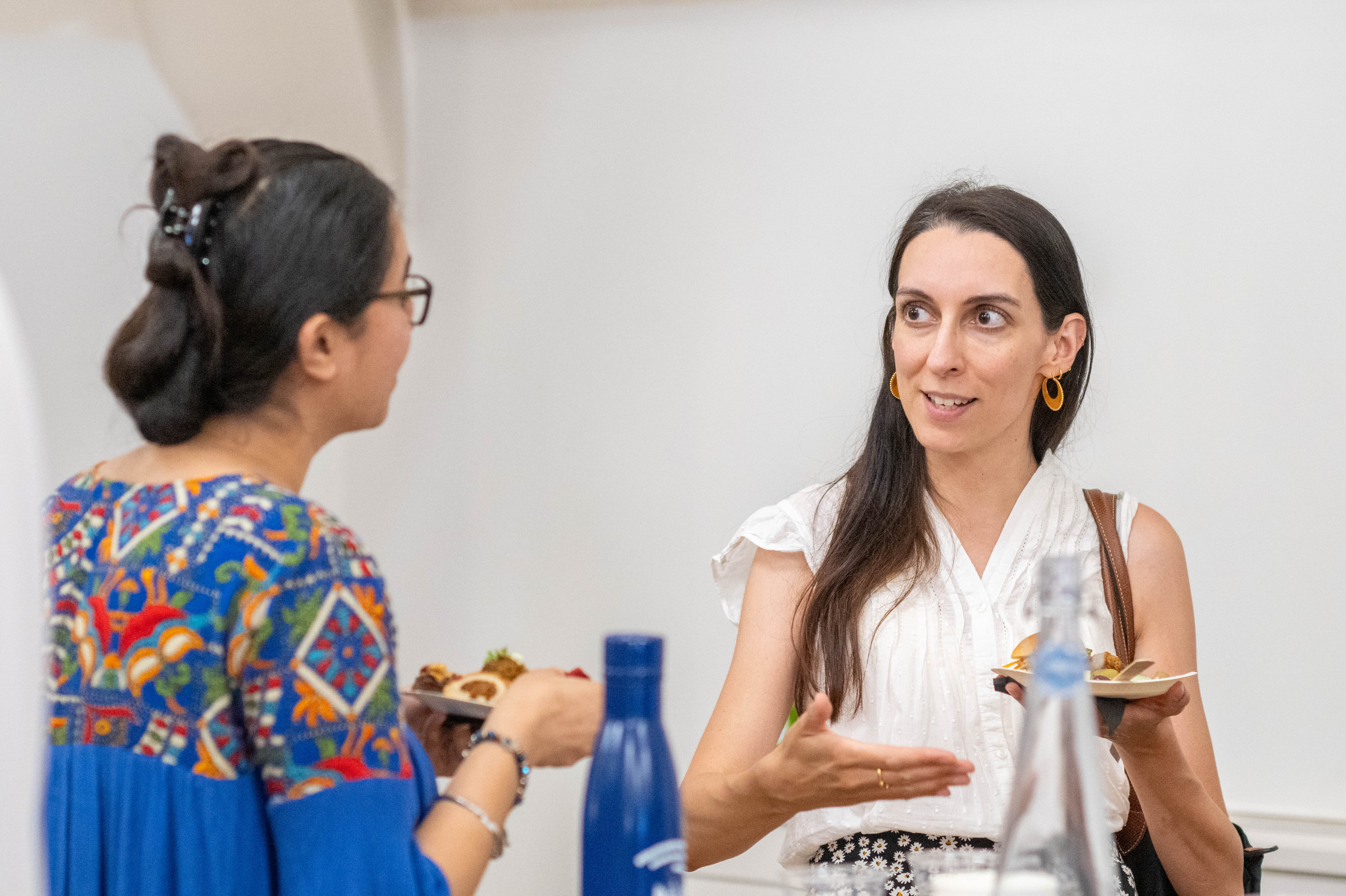 brown woman with dark hair speaking with a colleague using her hand to emote