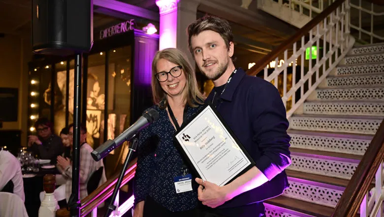 a female presenting person with a male presenting person holding a certificate