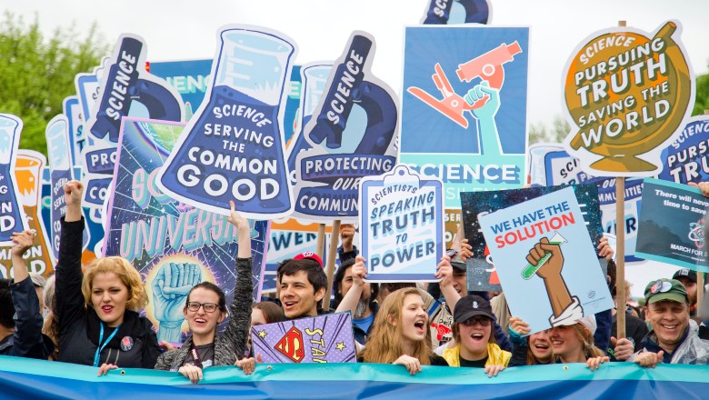 Protesters marching with signs about trusting science and scientists