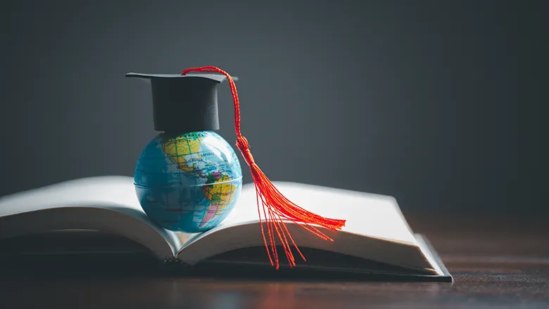Globe toy with graduation cap on a book