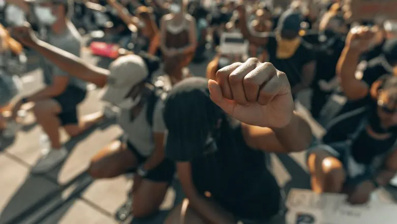 Protesters kneeling and fists in the air - by clay banks - 780x440