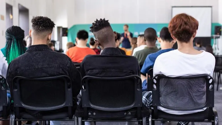 Photo of the backs of three boys sitting at the back of a classroom.