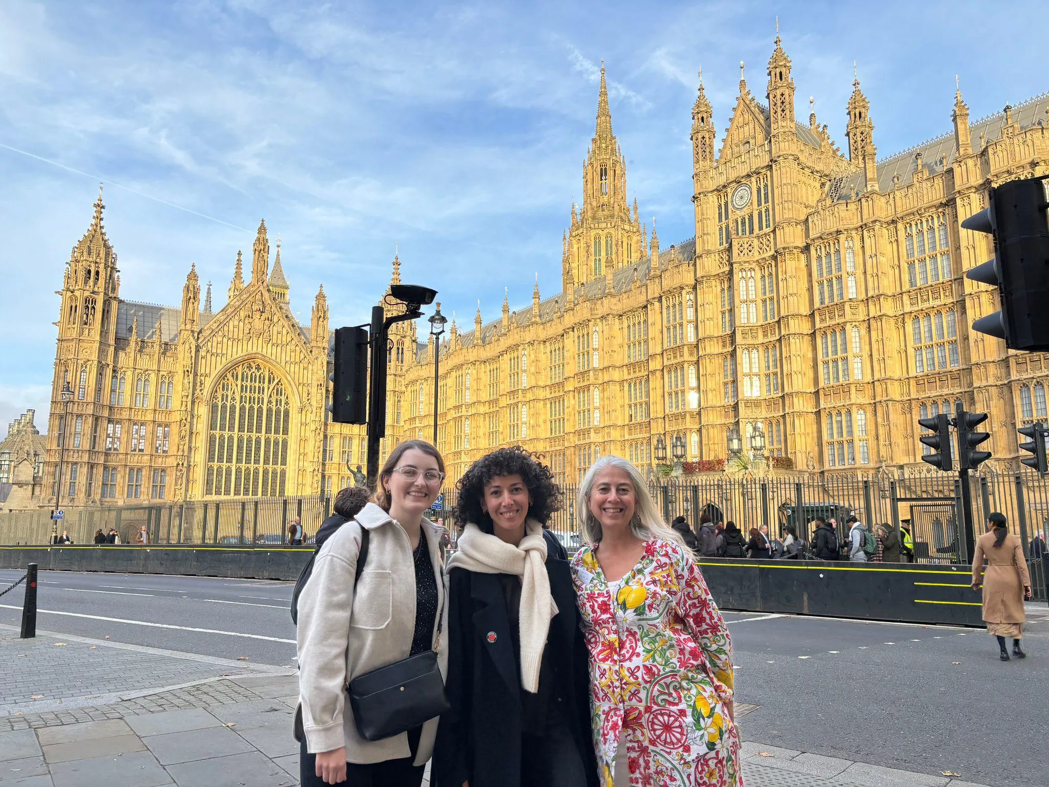 three women stood outside houses of parliament